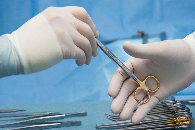 Surgical tool being passed between two gloved hands
