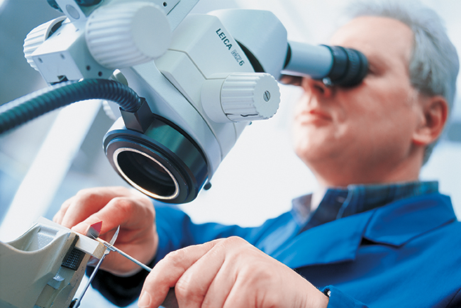 Aesculap technician examining surgical scissors through microscope