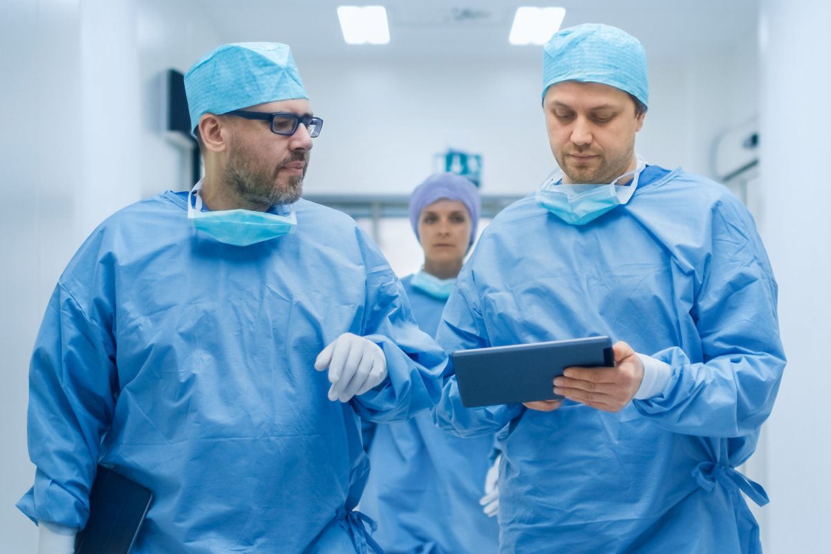 Two men in scrubs looking at computer tablet